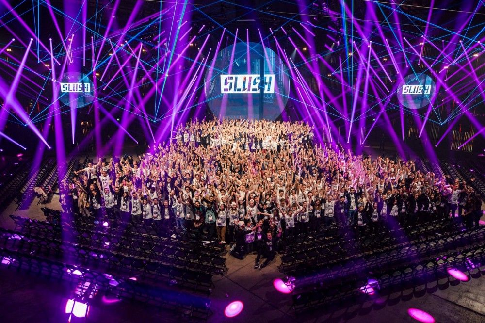 A large group of people wearing white t-shirts, purple light show