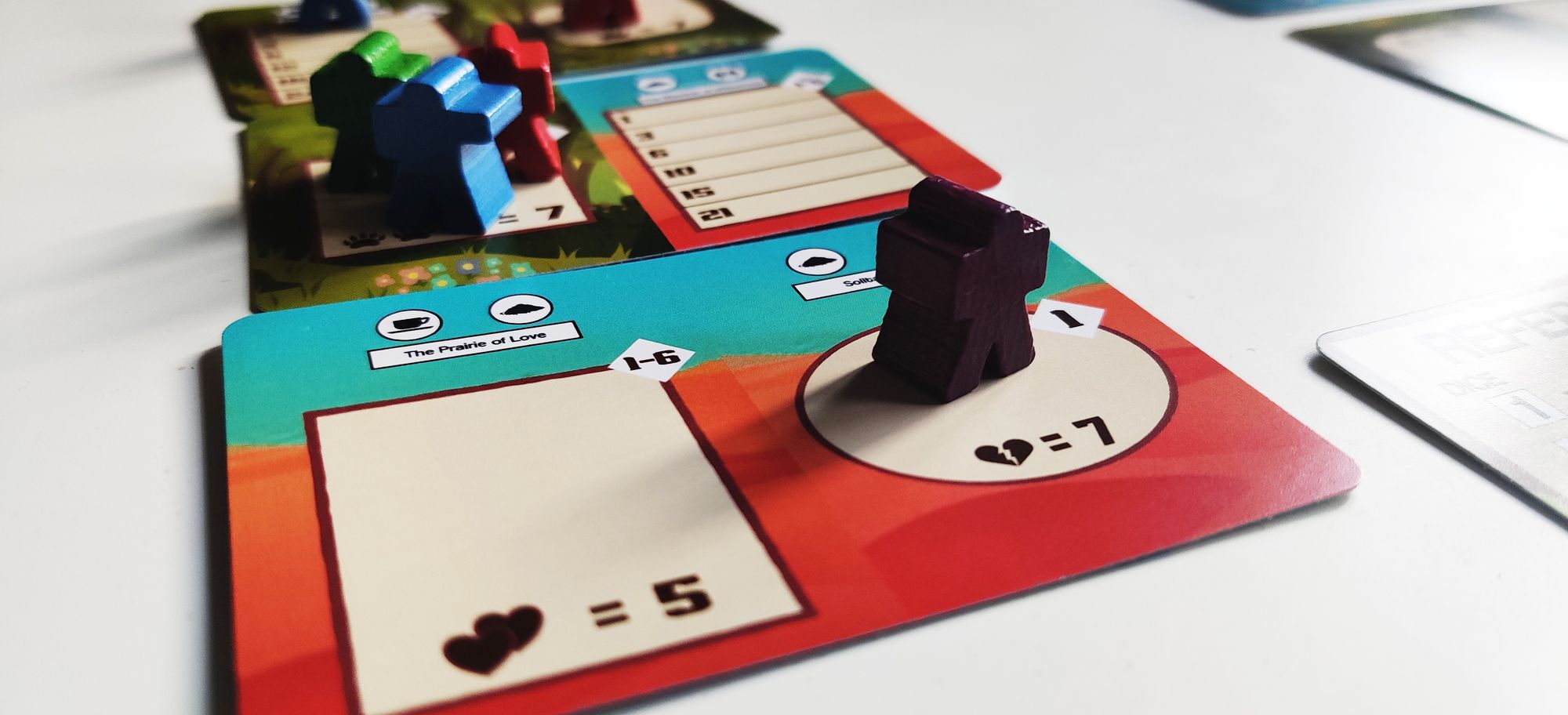 A black meeple standing in a circular pen in Draftosaurus card with other meeples standing in the background