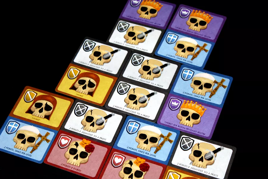A pyramid of colorful cards with pictures of skulls wearing different kind of apparel like crowns, crosses, roses, daggers and hoods.