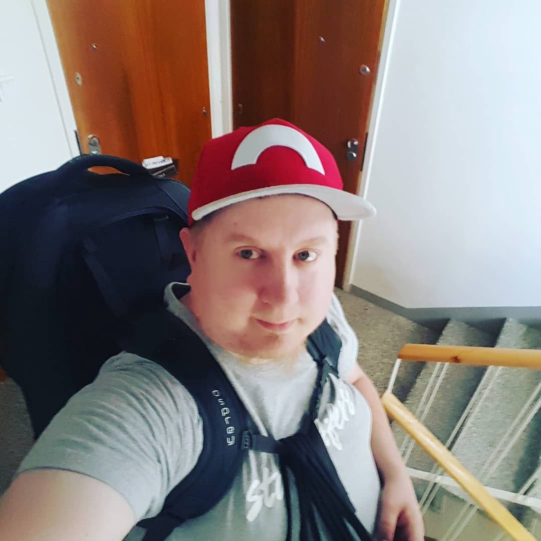 A selfie in staircase of me wearing a red cap and a backpack