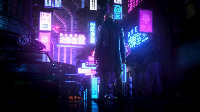Agent 47 standing in a long black coat in a dark city with a lot of blue and pink neon lights on buildings