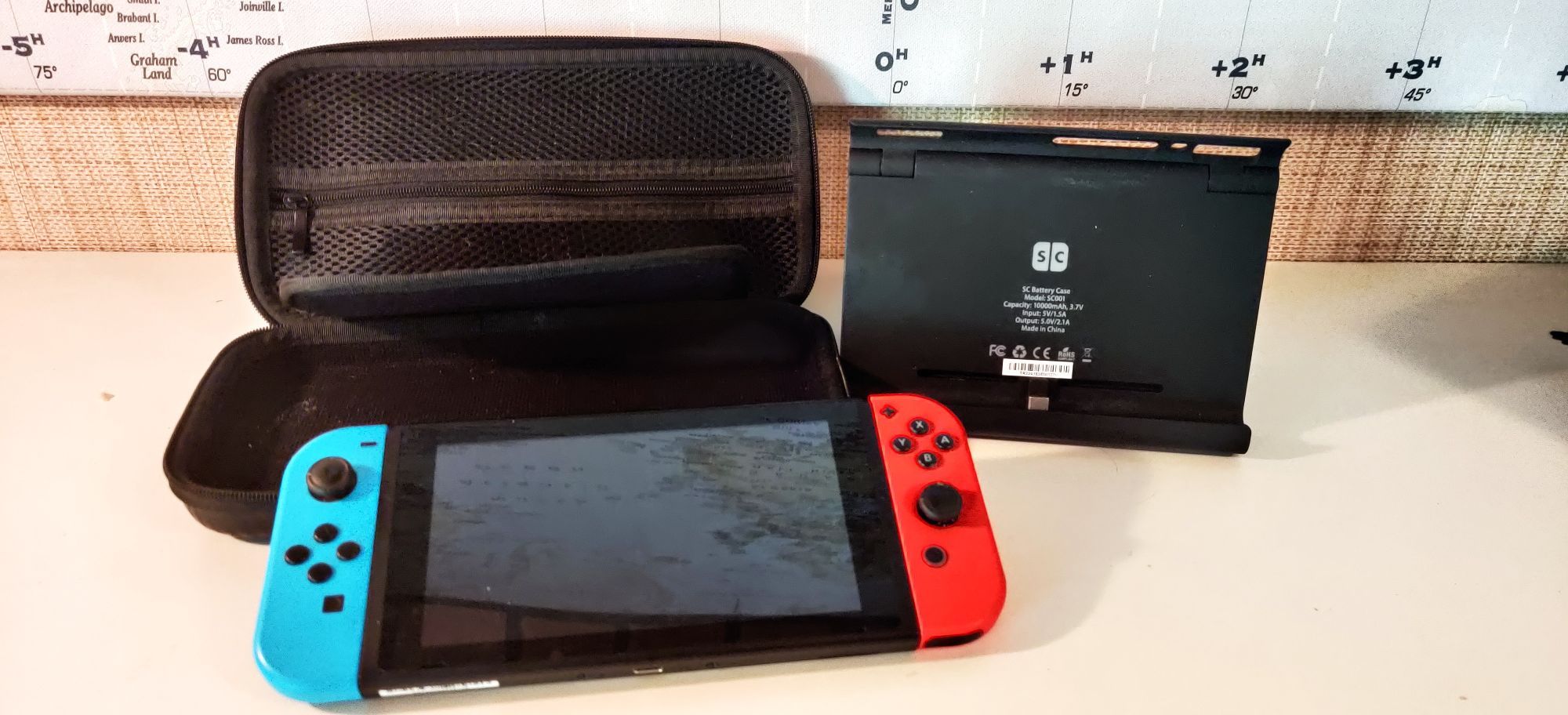 A Nintendo Switch next to a powerbank and a carrying case that's same size as Switch