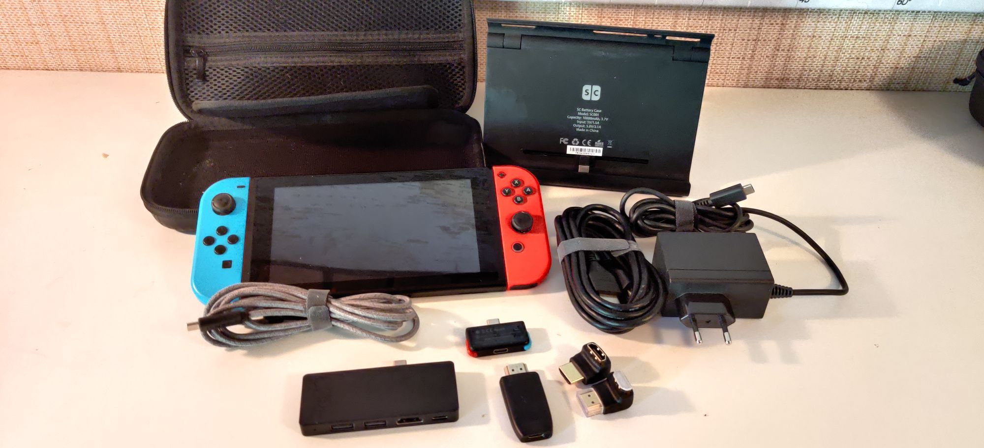 A Nintendo Switch, a powerbank, a carrying case, a charger, HDMI cable, USB-C cable, small dock, capture card, bluetooth headset receiver and two 90 degree HDMI adapters