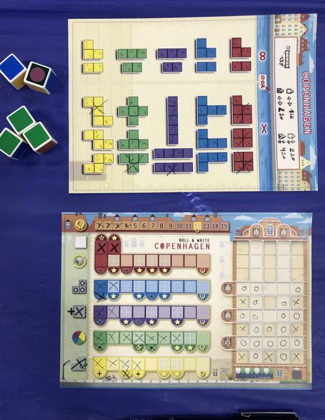 A board on top displaying different geometrical shapes and a bottom board with mid-game progress of Copenhagen