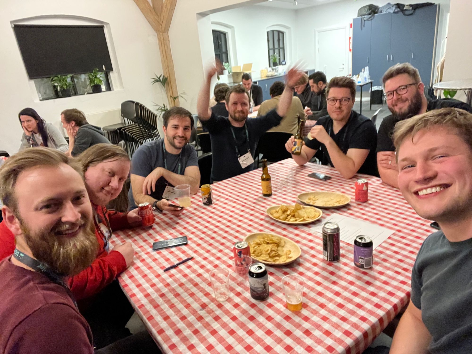 A group of people laughing around a table, looking into the camera