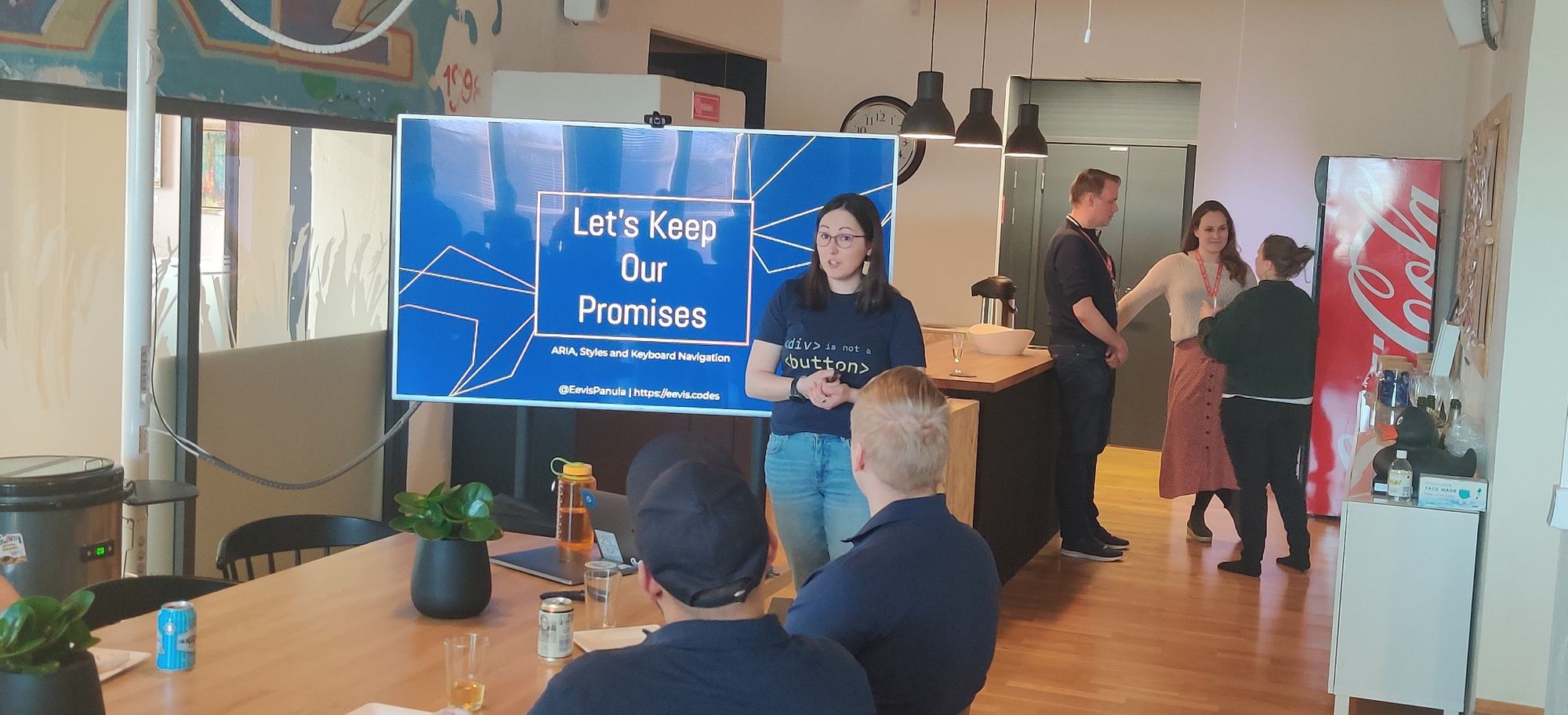 Eevis speaking in front of meetup audience with a slide that says "Let's keep our promises"