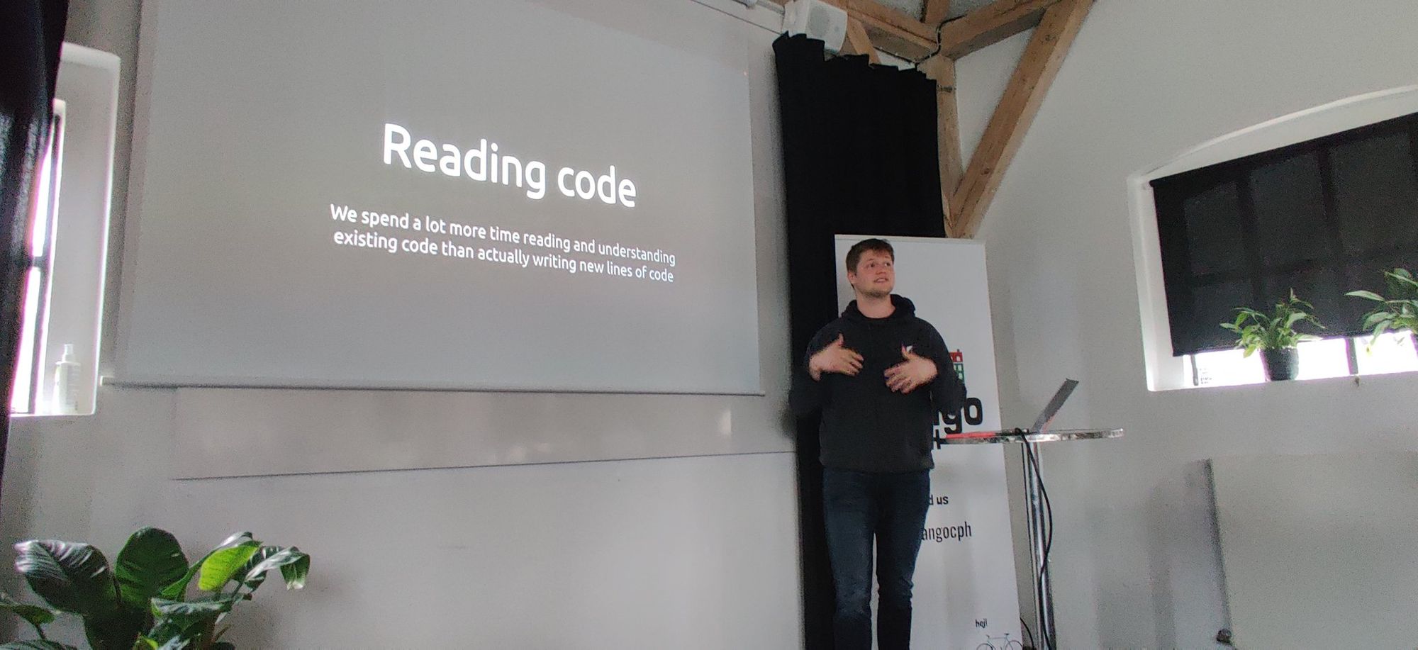 Wilhelm speaking on stage with a slide about how much more we read code than we write it