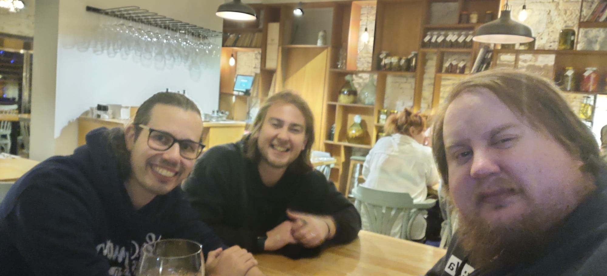 Three men sitting in a restaurant, taking a group selfie and smiling