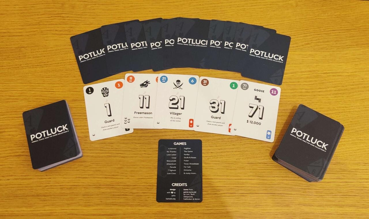 A deck with a few cards fanned out face-down, showing a dark blue background with white logo saying Potluck. Below them, five white cards face up showing numbers 1, 11, 21, 31 and 71 and a variety of other elements in the cards.  Below them, a single card listing a bunch of games and credits for the project.