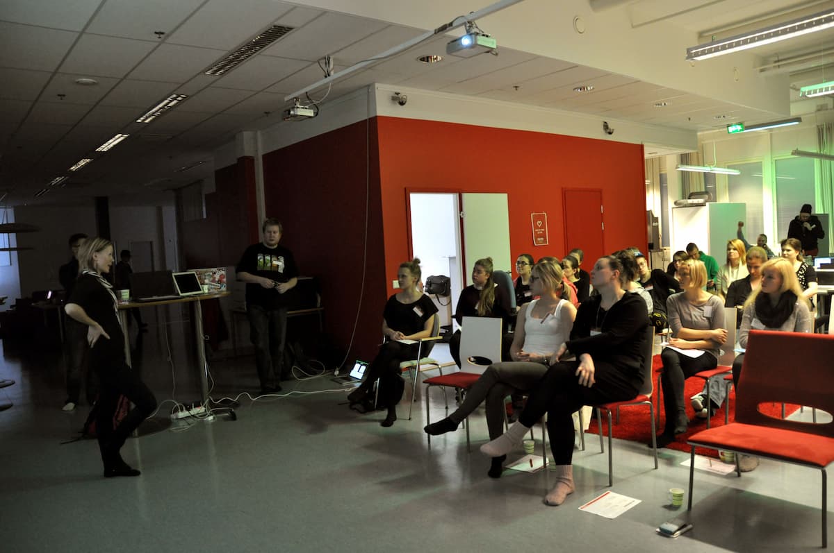 A group of people, mostly women, listening to a speaker in a room