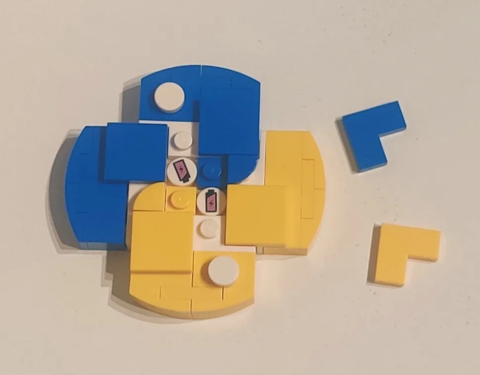 A LEGO Python logo with two pieces removed to the side, exposing two 1-by-1 circle pieces with battery stickers inside the logo. 