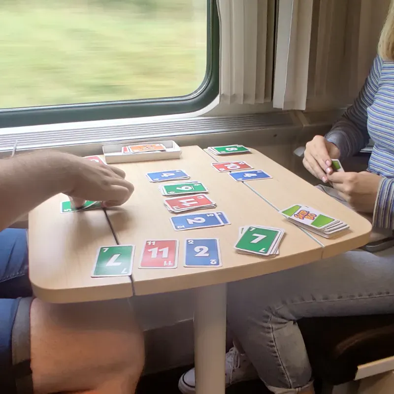 An on-going three player Skip-Bo game on a train table   