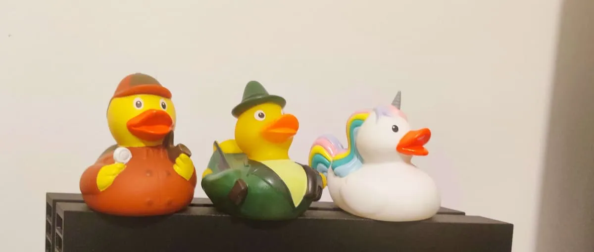 Three rubber ducks on top of a Playstation: one that looks like Sherlock Holmes, another is a hunter and third is
    unicorn. 