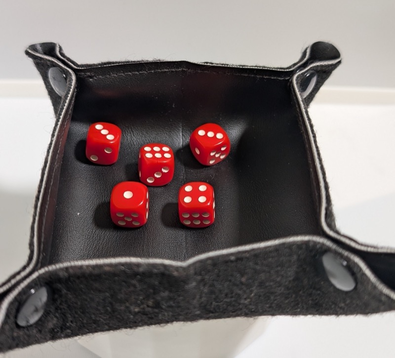 A foldable cloth-and-leather dice tray with five small red dice in it. 