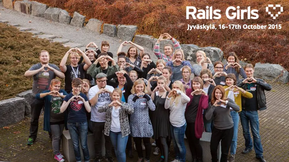 A group photo of roughly 30 people standing outside. Everyone is making a heart sign with their hands.