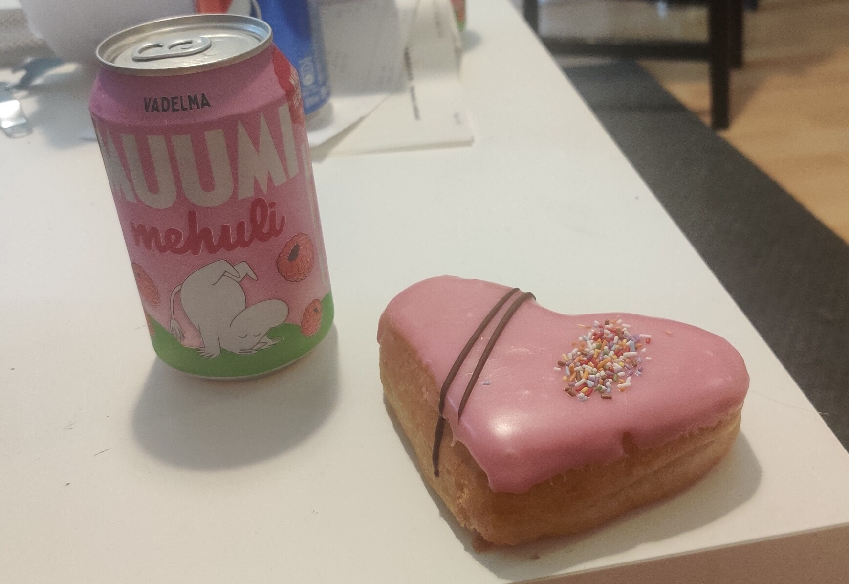A pink Muumi Mehuli soda can and a pink donut. 