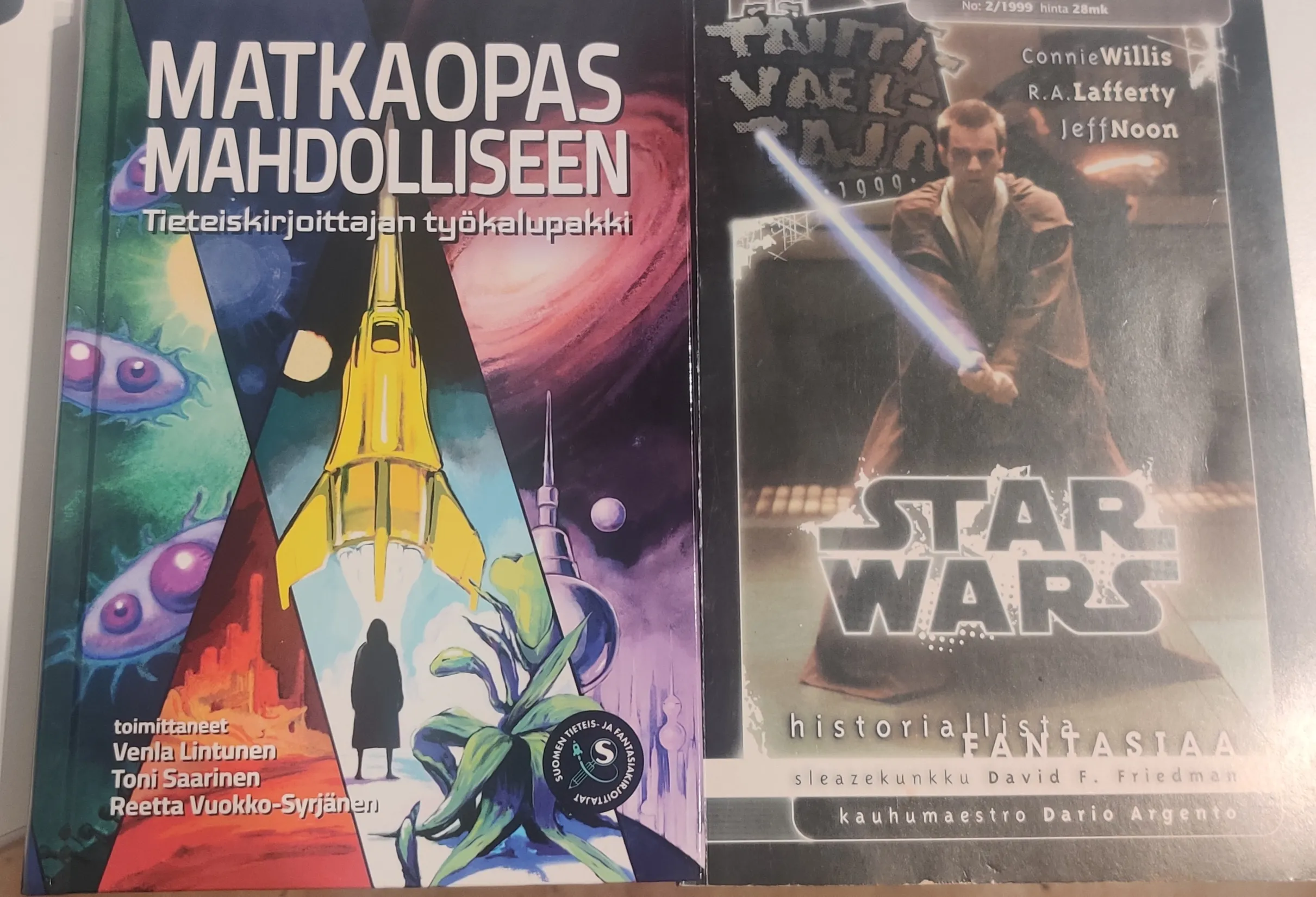 A book called Matkaopas mahdolliseen with a colourful collage of scifi themed illustrations and a magazine Tähtivaeltaja with Obi-Wan Kenobi from Phantom Menace on the cover. 