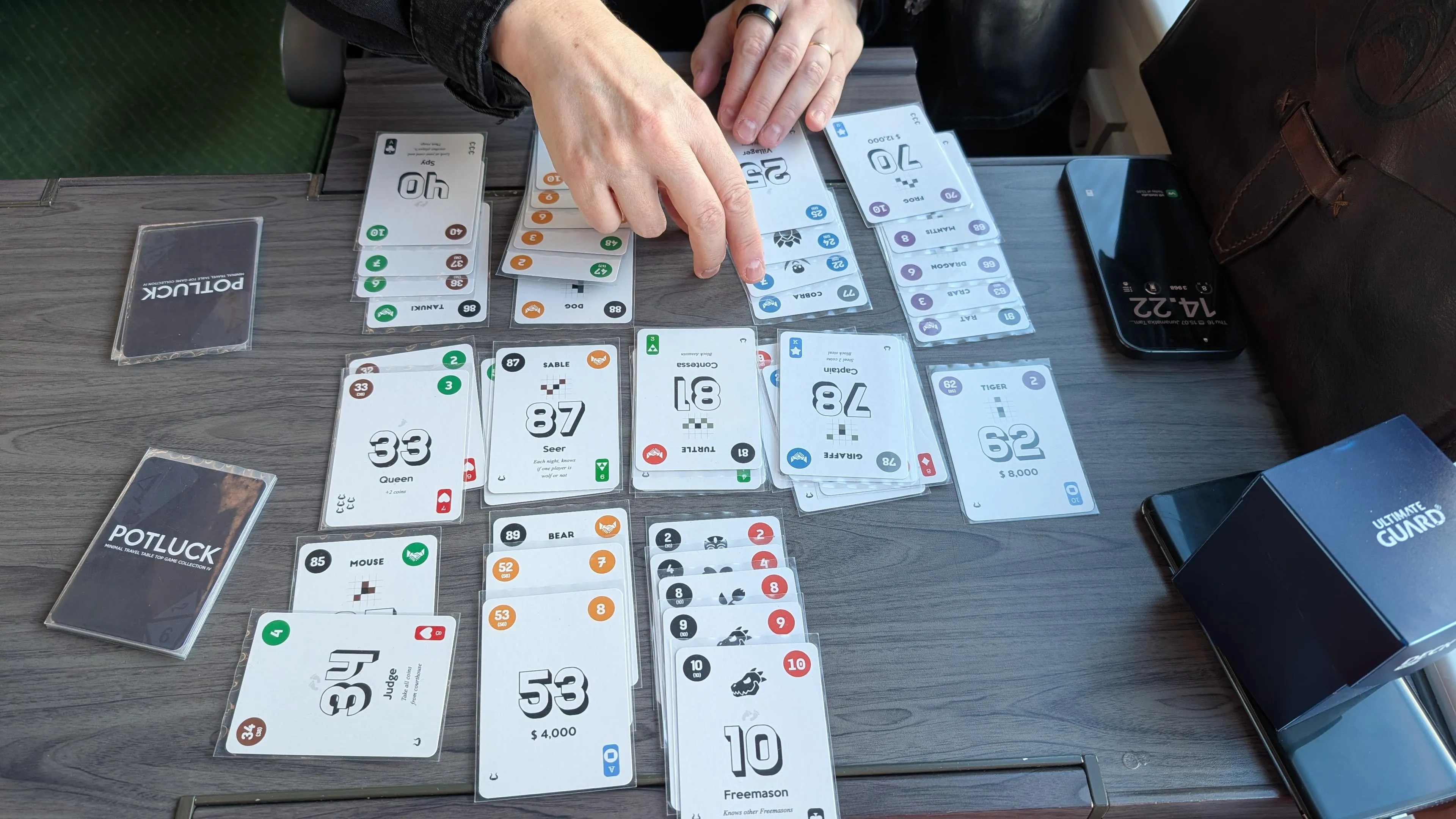 Lost Cities card game being played in a train table. Cards in five colours are organised in columns based on their colors so that both players have their own columns where numbers are played in ascending order.