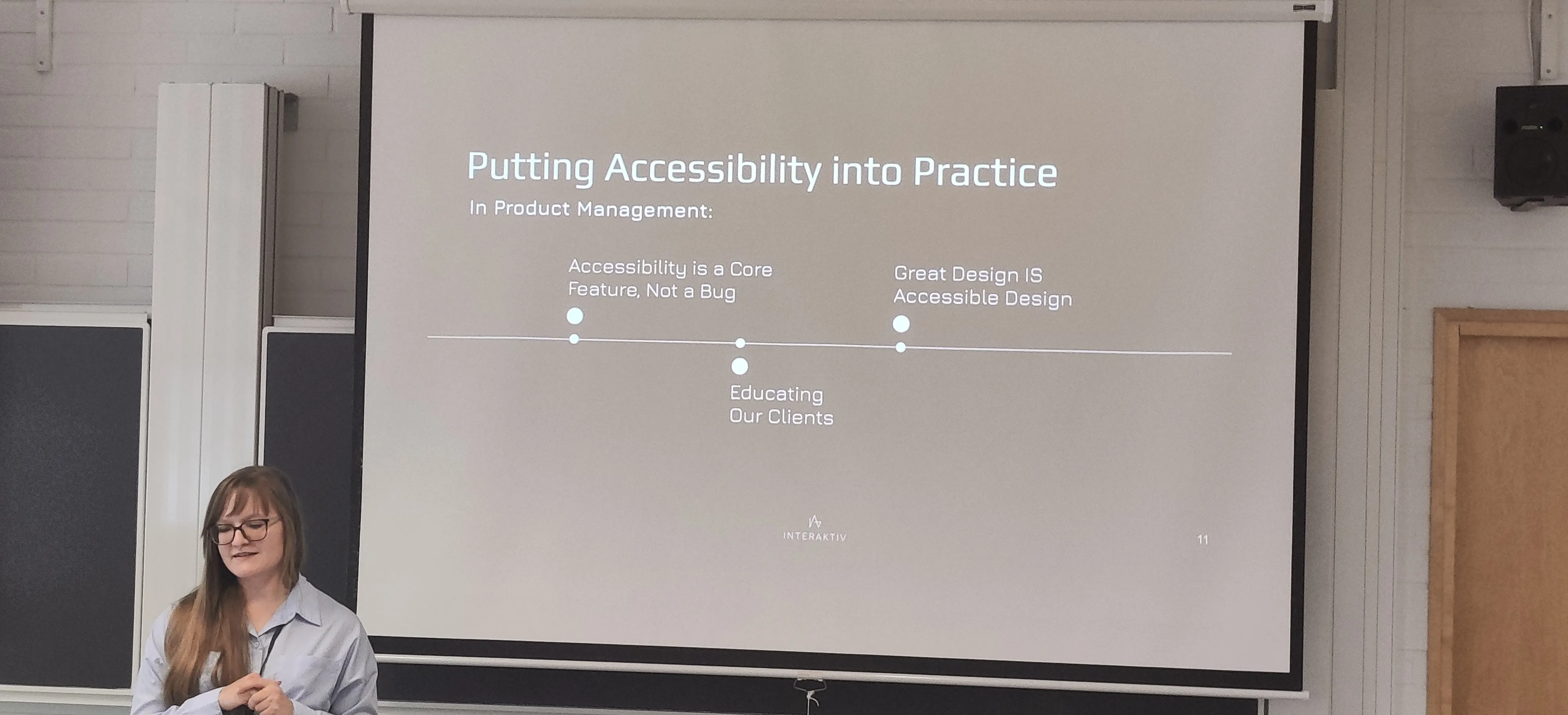 Karin presenting in front of a room with a slide about Putting accessibility into practice.