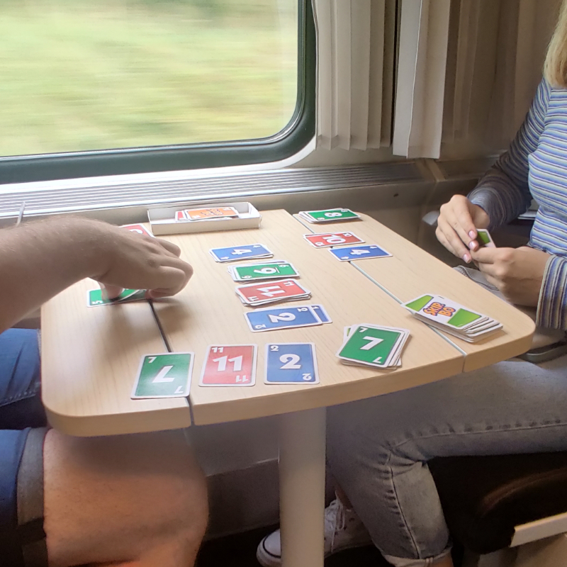 An on-going three player Skip-Bo game on a train table  