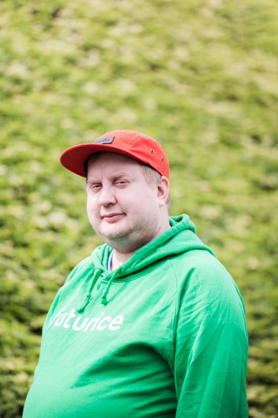 Juhis looking at the camera, wearing green hoodie. Blurred green background