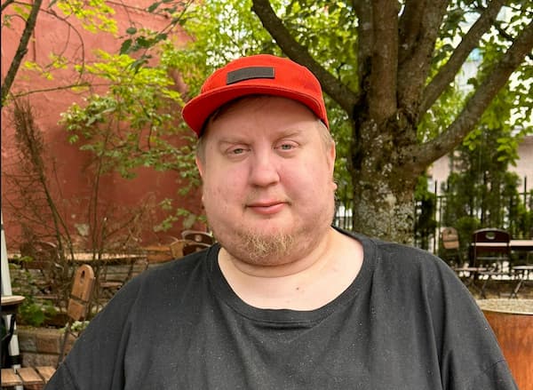 Portrait of Juhis outside in the summer with a red cap and black shirt