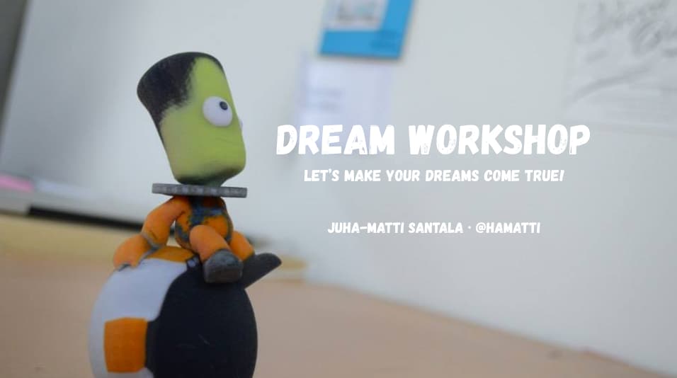 3D printed Kerbal figure, blurred background with text Dream Workshop, Let's make your dreams come true! overlayed on top